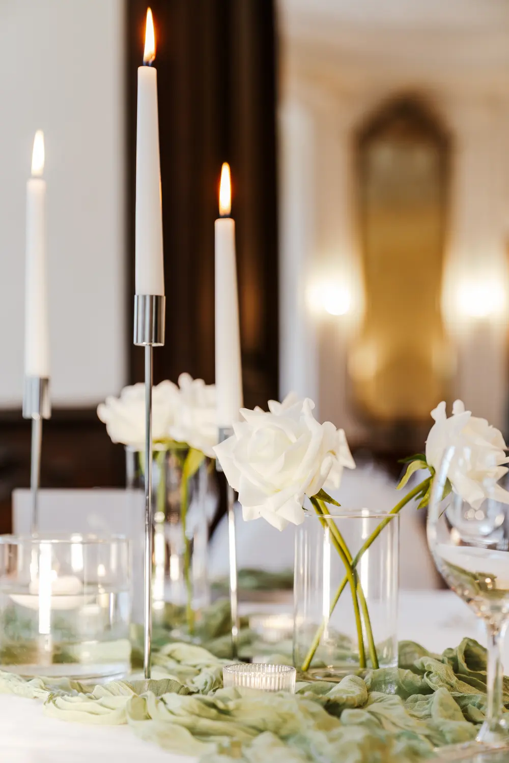 Gedeckte Tafel mit Silber-Kerzenständern und weißen Rosen